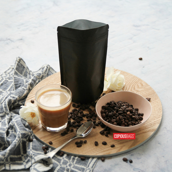 Black pouch next to cup of latte and coffee beans