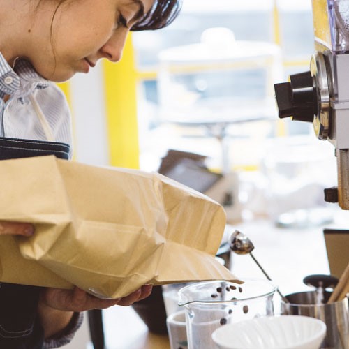 Coffee barista serving coffee beans from a kraft bag